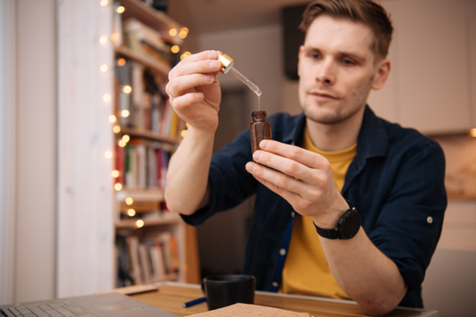 Vitamins and supplements. Hand holding pipette of Hemp oil. Close up man uses CBD oil. Medical cannabis.